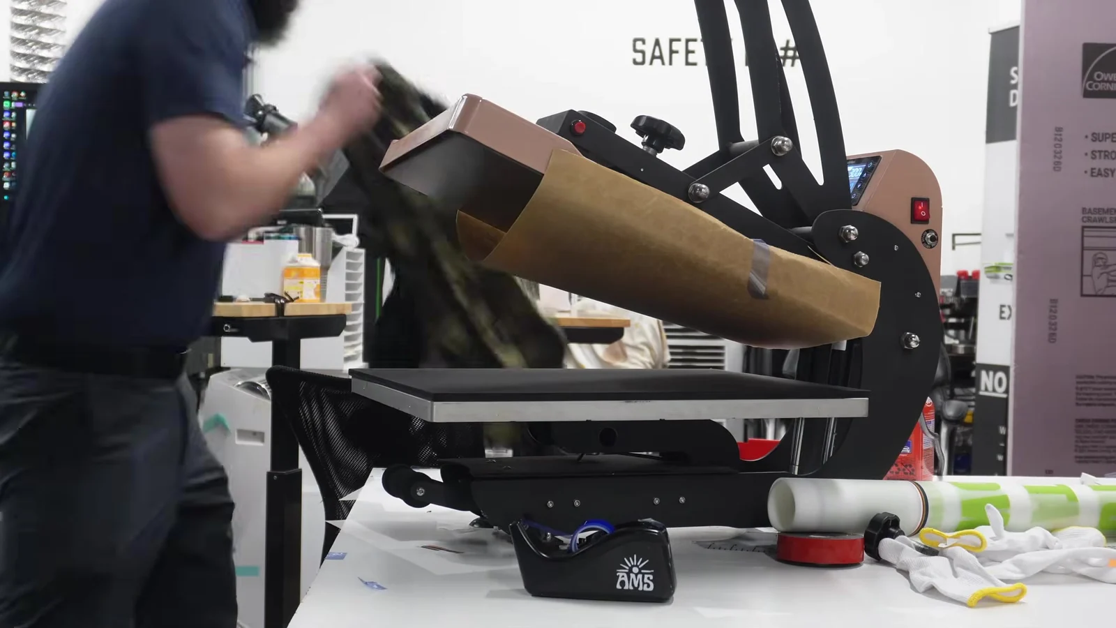 Black polyester and camo shirts shown on the heat press during AMS DTF powder test